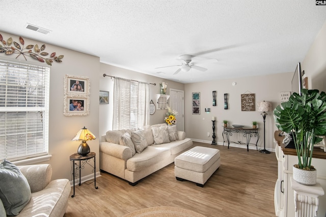 living area with light wood-type flooring, visible vents, plenty of natural light, and a textured ceiling