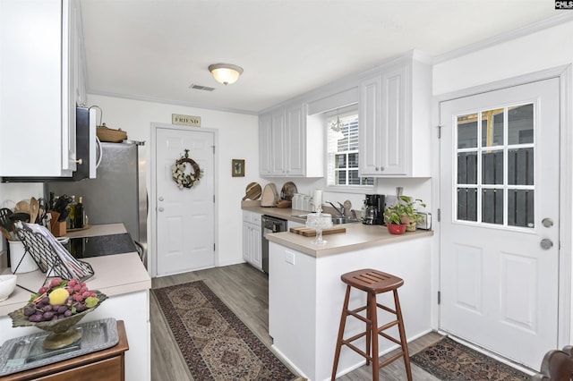 kitchen featuring visible vents, dark wood-type flooring, a peninsula, white cabinetry, and a sink