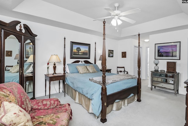 bedroom featuring light carpet, ceiling fan, and a tray ceiling