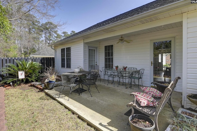 view of patio with a ceiling fan, outdoor dining space, and fence