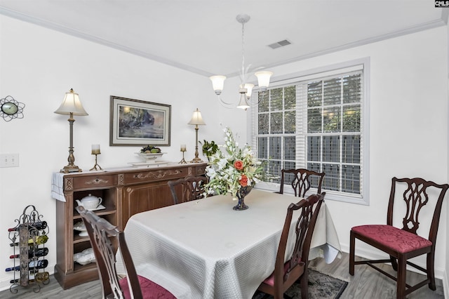 dining room featuring visible vents, an inviting chandelier, ornamental molding, wood finished floors, and baseboards