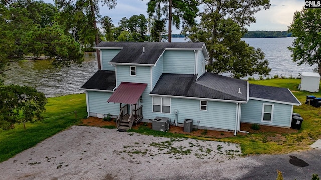 rear view of house featuring central AC unit, a water view, and a shingled roof