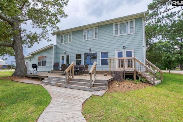 rear view of property featuring a wooden deck, a lawn, and french doors