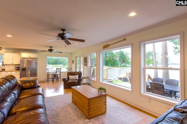 living area with ornamental molding, recessed lighting, baseboards, and light wood finished floors