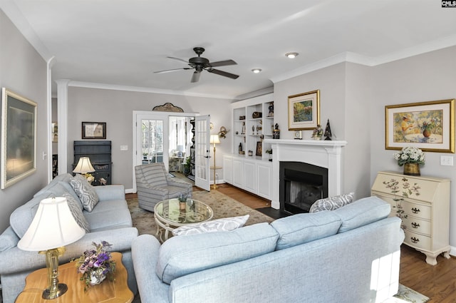 living area featuring dark wood-style floors, crown molding, a fireplace with flush hearth, and a ceiling fan