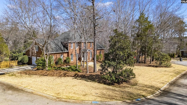 view of front of property featuring driveway, a garage, fence, and brick siding