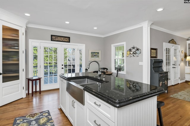 kitchen with french doors, crown molding, white cabinetry, a sink, and wood finished floors