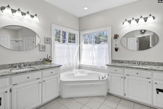 full bath featuring two vanities, a garden tub, a sink, and tile patterned floors