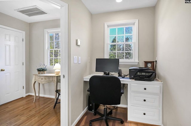 office space featuring baseboards, visible vents, and wood finished floors