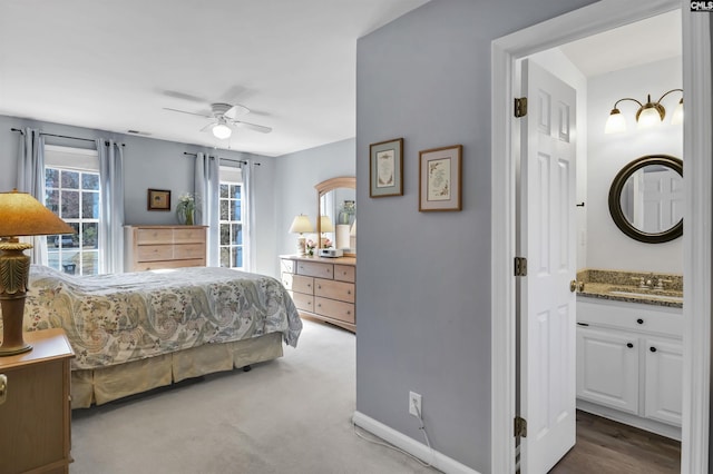 bedroom featuring ceiling fan, a sink, visible vents, baseboards, and carpet