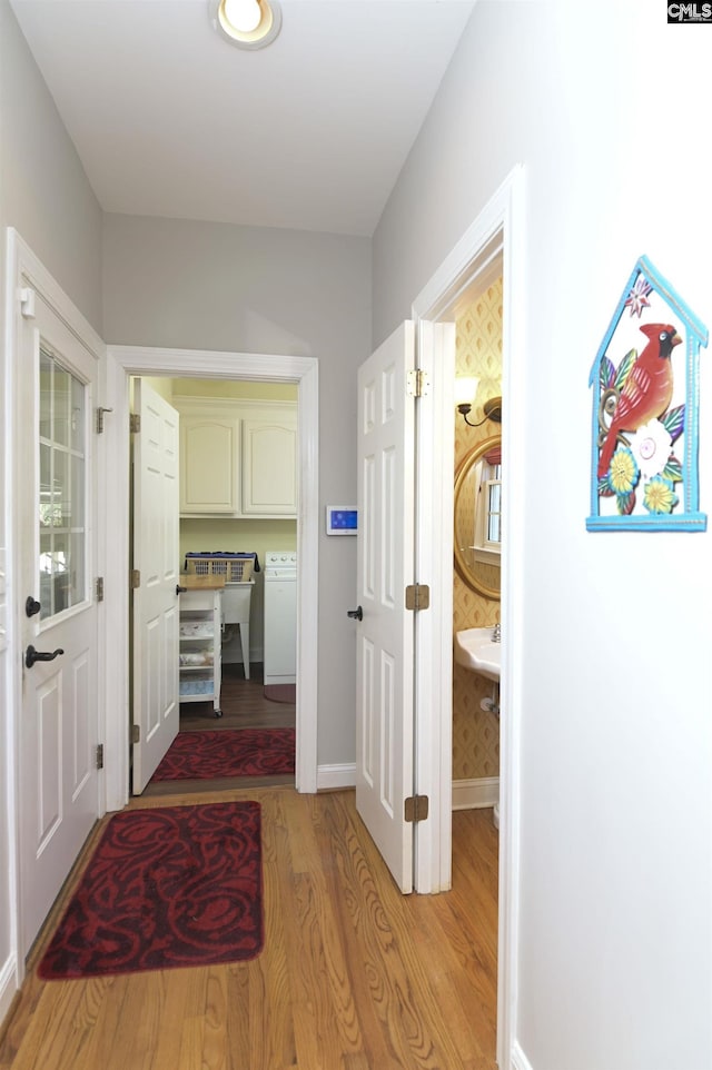 hallway featuring light wood-style flooring, washer / clothes dryer, and baseboards