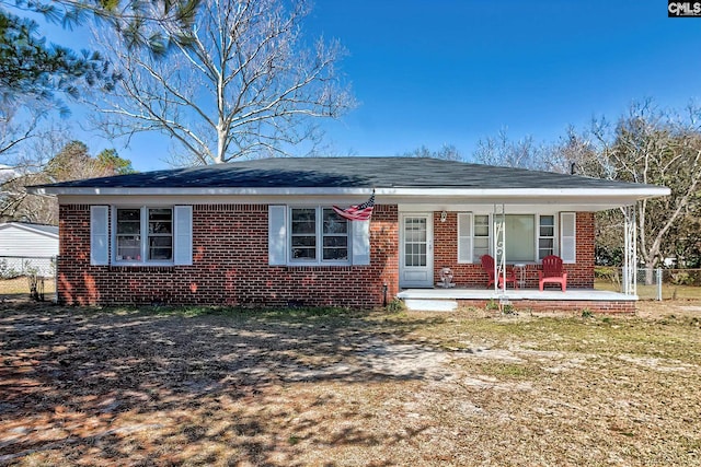 ranch-style home featuring covered porch, fence, and brick siding