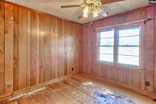 unfurnished room featuring wood walls, a textured ceiling, and hardwood / wood-style floors