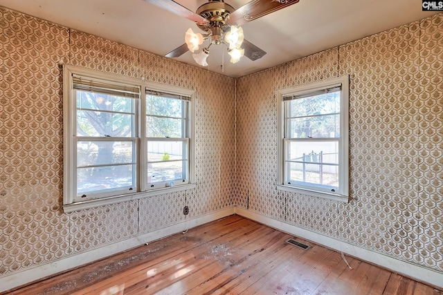 unfurnished room with wallpapered walls, baseboards, visible vents, ceiling fan, and light wood-style floors