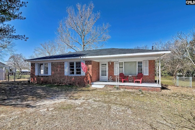 view of front of property with covered porch, brick siding, fence, and a gate