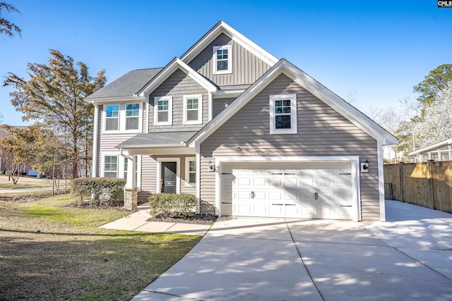 view of front of home with driveway, an attached garage, fence, a front lawn, and board and batten siding