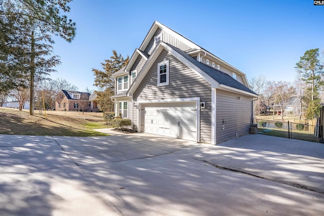 view of side of property featuring driveway, a garage, and fence