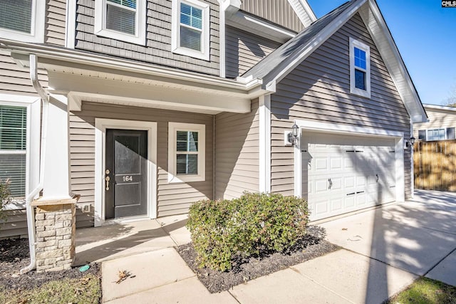 view of exterior entry with a garage, board and batten siding, and concrete driveway