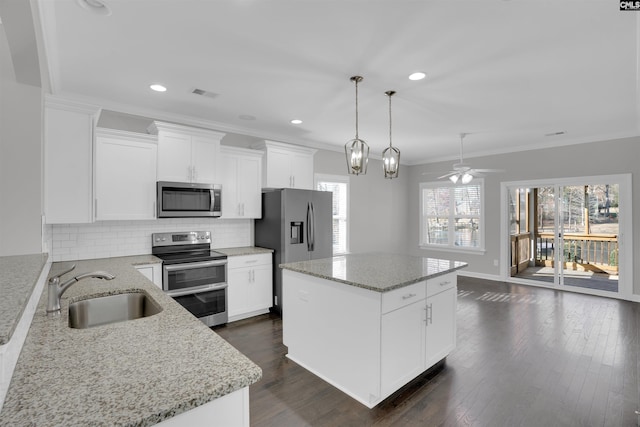 kitchen featuring stainless steel appliances, visible vents, backsplash, a sink, and a kitchen island