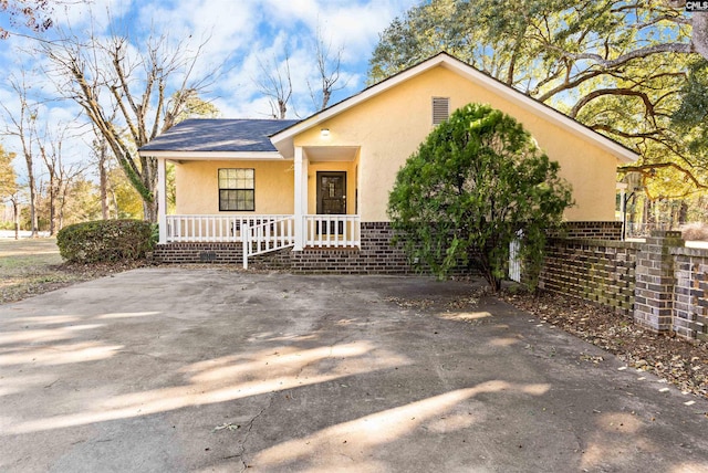 view of front of property featuring a porch, a shingled roof, fence, and stucco siding