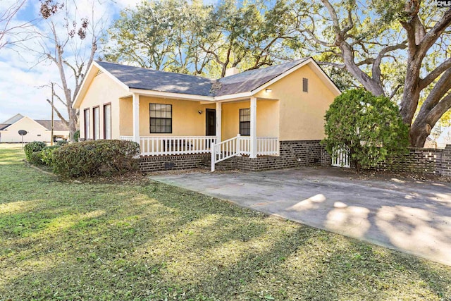 ranch-style home with covered porch, a front lawn, and stucco siding