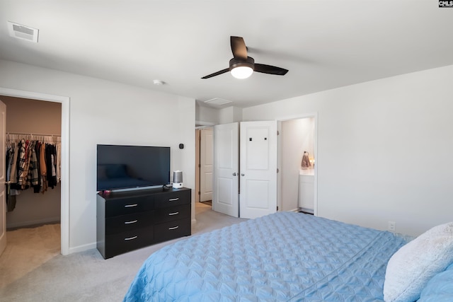 bedroom with a closet, light colored carpet, a spacious closet, attic access, and a ceiling fan