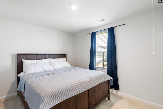 bedroom featuring visible vents, light carpet, and baseboards