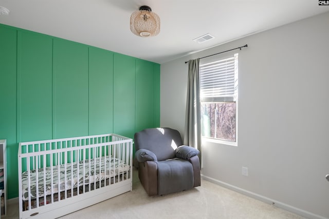 carpeted bedroom with a nursery area, visible vents, and baseboards