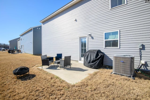 back of house with a yard, an outdoor living space with a fire pit, central AC, and a patio