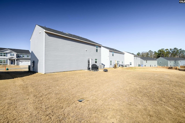 back of property with a residential view, central AC, and a yard