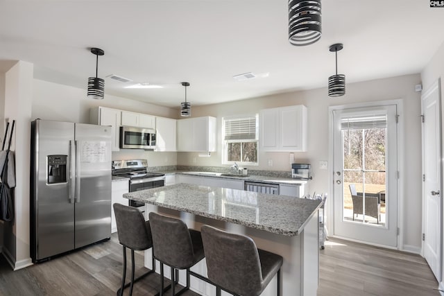 kitchen with white cabinets, stainless steel appliances, dark wood-style flooring, and a center island