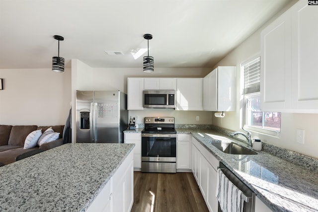 kitchen featuring light stone counters, a sink, visible vents, appliances with stainless steel finishes, and dark wood finished floors