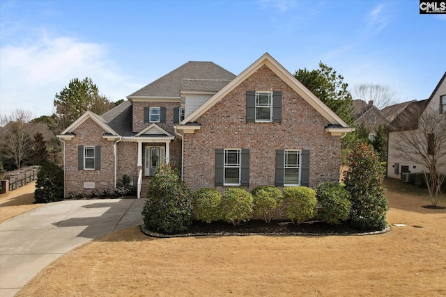 view of front facade featuring crawl space, roof with shingles, cooling unit, and brick siding