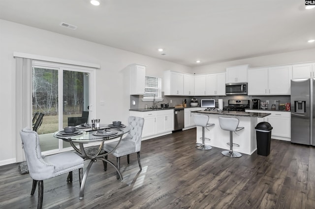 kitchen with stainless steel appliances, plenty of natural light, dark countertops, and visible vents