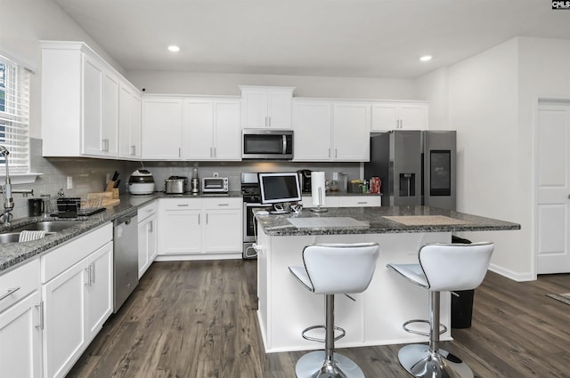 kitchen with dark wood-type flooring, backsplash, a center island, stainless steel appliances, and white cabinets