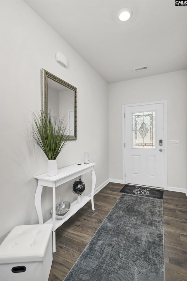 foyer entrance featuring visible vents, baseboards, and dark wood-style flooring