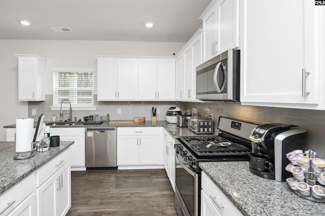 kitchen featuring visible vents, dark wood-type flooring, white cabinets, stainless steel appliances, and a sink