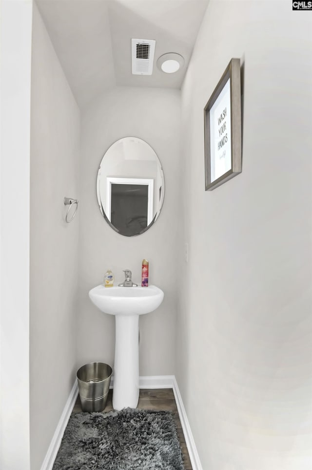 bathroom featuring visible vents, a sink, baseboards, and wood finished floors