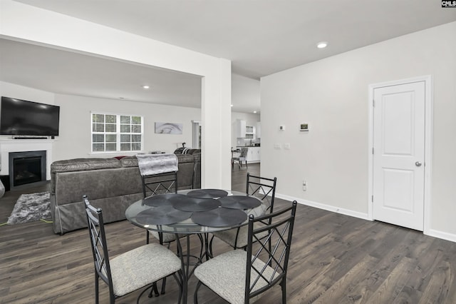 dining space featuring recessed lighting, baseboards, dark wood-type flooring, and a fireplace