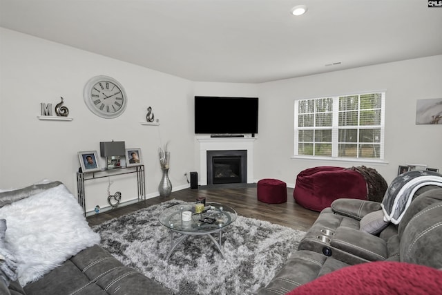 living room with wood finished floors, visible vents, baseboards, recessed lighting, and a glass covered fireplace