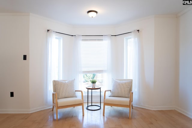 living area featuring light wood-style floors, crown molding, and baseboards