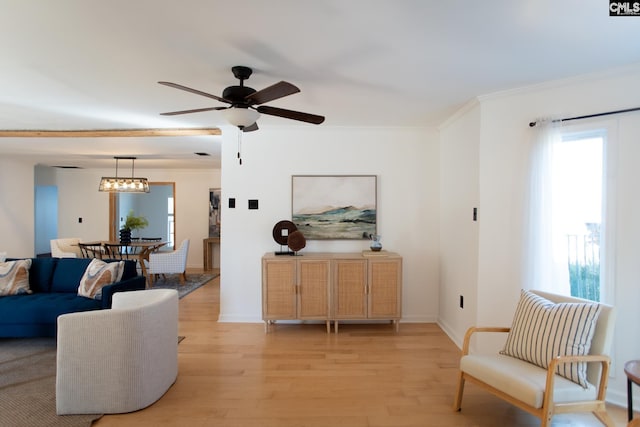 living room with light wood-type flooring, crown molding, baseboards, and ceiling fan