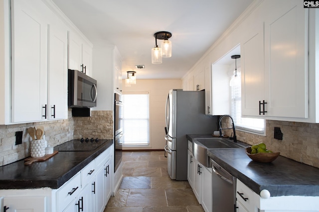 kitchen featuring appliances with stainless steel finishes, dark countertops, stone tile flooring, and white cabinets