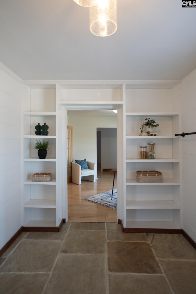 hallway with built in features, stone finish flooring, and baseboards