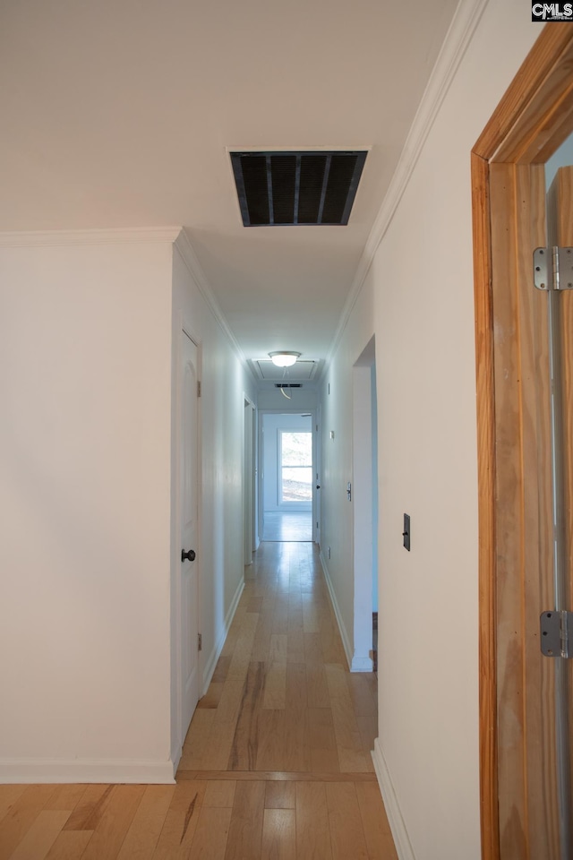 hallway featuring light wood-type flooring, baseboards, visible vents, and ornamental molding