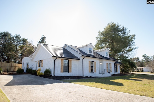 view of front of property with metal roof, brick siding, fence, a front lawn, and a standing seam roof