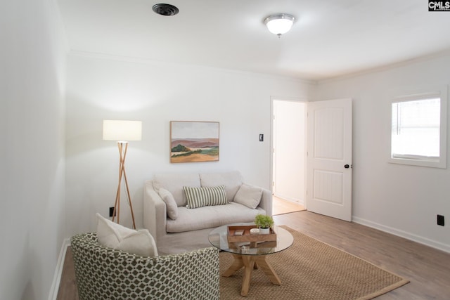 living area featuring crown molding, baseboards, and light wood-style floors