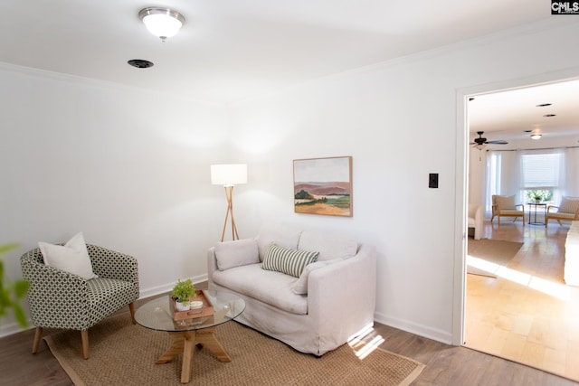 living room with baseboards, ornamental molding, and wood finished floors