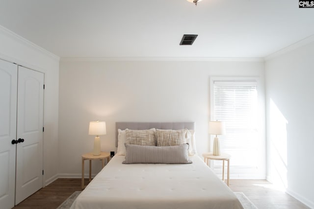 bedroom featuring ornamental molding, a closet, visible vents, and wood finished floors