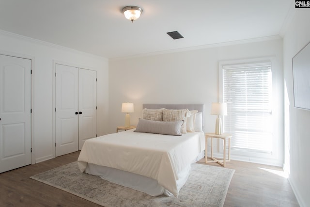 bedroom with ornamental molding, wood finished floors, visible vents, and baseboards